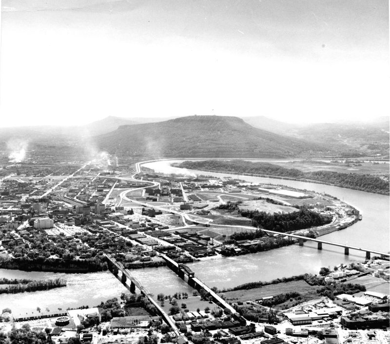 Aerial view of Chattanooga from north shore of the Tennessee River showing Walnut Street, Market Street (Chief John Ross) and Olgiati Bridges, foot of Moccasin Bend with Lookout Mountain in background.