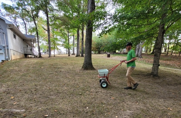 A member of The Galloway Team spreading grass seed in a Chattanooga yard.